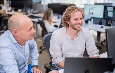 Collega's van SWIS overleggen achter een beeldscherm